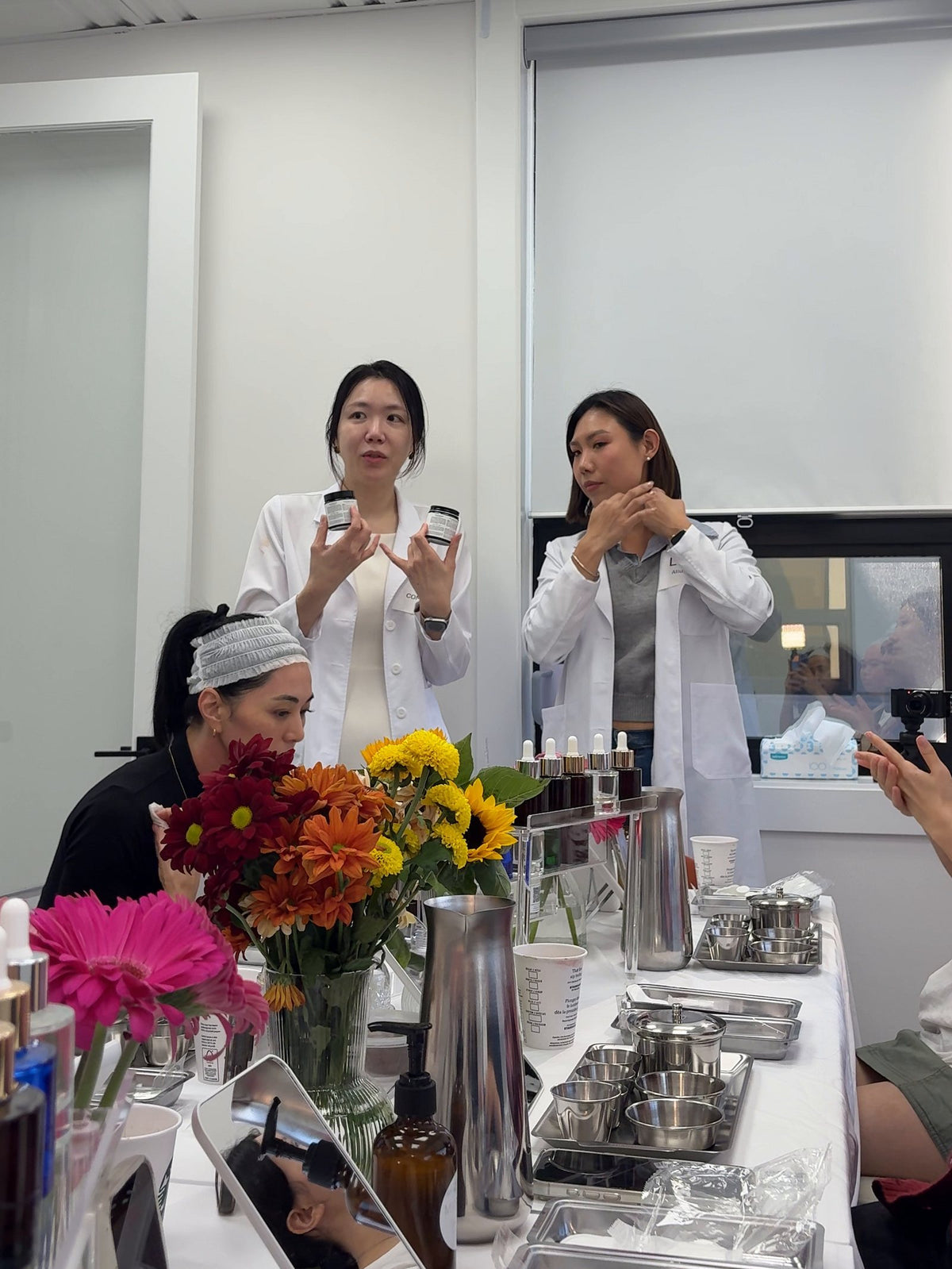 Founder Clara Song presenting products to a table of creators, with flowers and testing stations in front
